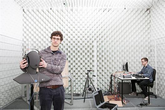 Dieses Bild zeigt zwei männliche Studierende in einem akustischen Testraum für Schallreflexionen des Fachbereichs Medien.